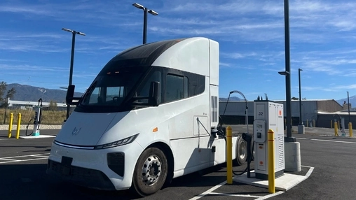Electric heavy-duty truck plugged into a Kempower MCS charging unit in a sunny California commercial lot